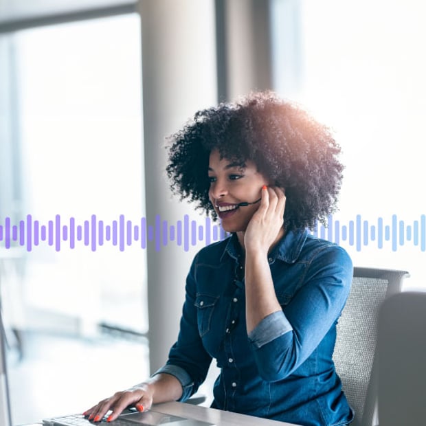 Photo of a smiling contact center agent talking to a customer through her phone headset. In the background, a series of small purple vertical lines run across the frame, representing conversation.