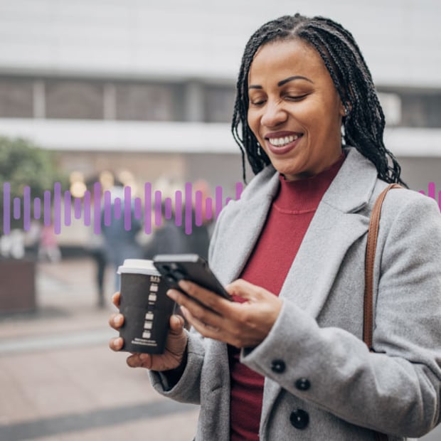 Photo of smiling woman outdoors using her phone to connect with a company