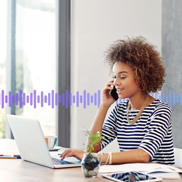 Photo of a woman in an office talking on her phone while typing on her laptop. Running across the frame in the background are a series of small purple vertical lines representing a voicemail recording.