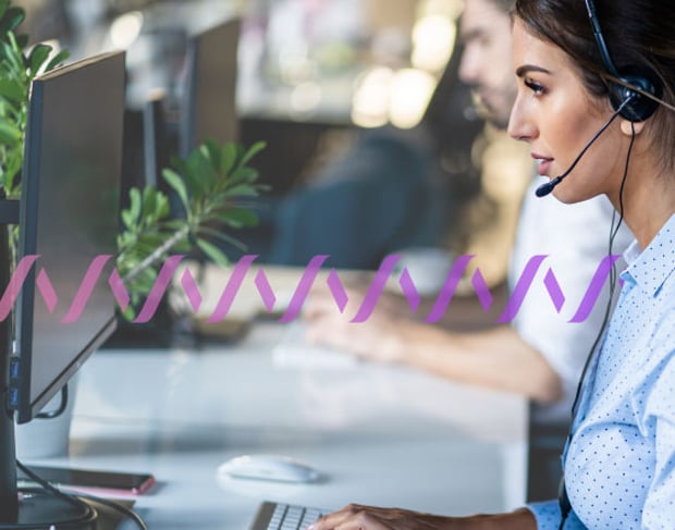 Photo of a row of contact center agents, seen from the side. They are talking to customers via their phone headsets while typing on their computers. In the background, a series of small purple waves runs across the frame.
