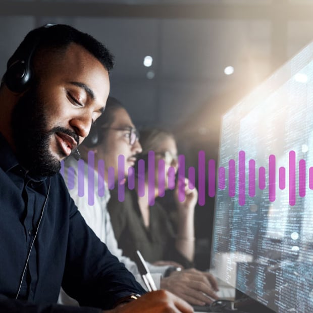 Man wearing a headset working in front of a computer screen displaying data, as a man and woman colleague work in the background.
